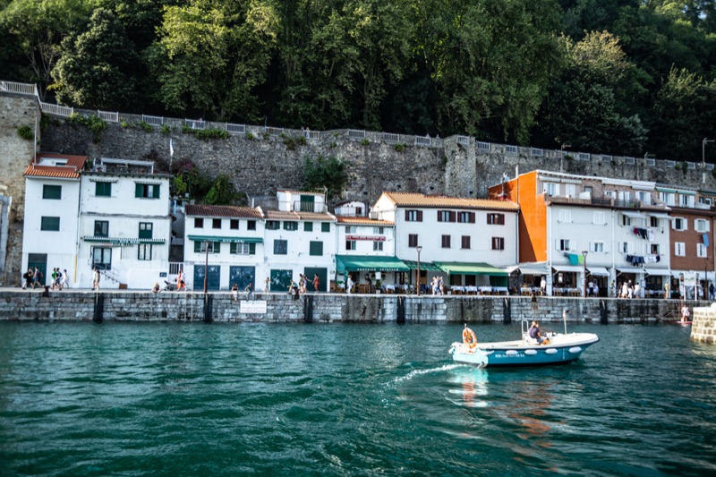 A view of San Sebastian port showing the traditional fish restaurants in front of the sea and a small boat coming into port